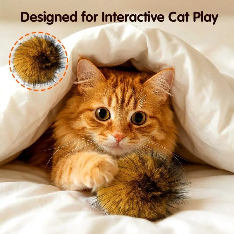 A fluffy orange tabby kitten peeks out from a white fabric, with an imitation rabbit fur cat toy ball visible.