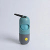 A teal and gray capsule dog waste bag dispenser with a black flashlight attachment.