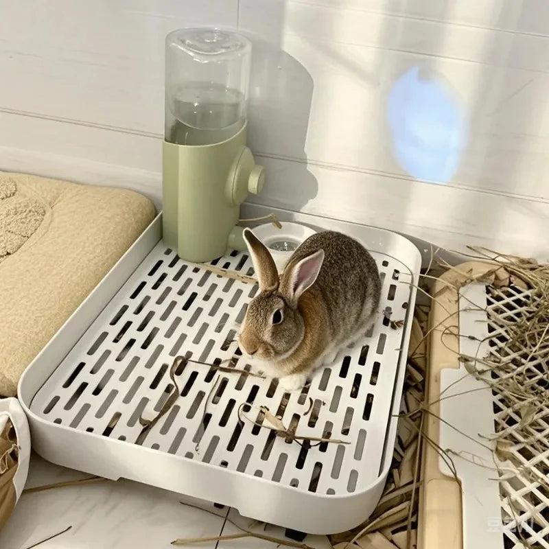 A white universal pet litter box for small animals with a clear water dispenser and natural bedding.