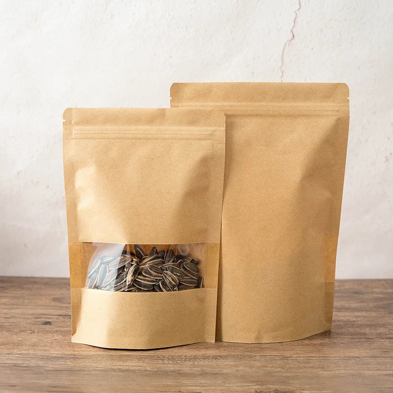 Zwei Kraftpapier-Zip-Beutel gefüllt mit getrockneten Kräutern oder Teeblättern auf einer Holzoberfläche.