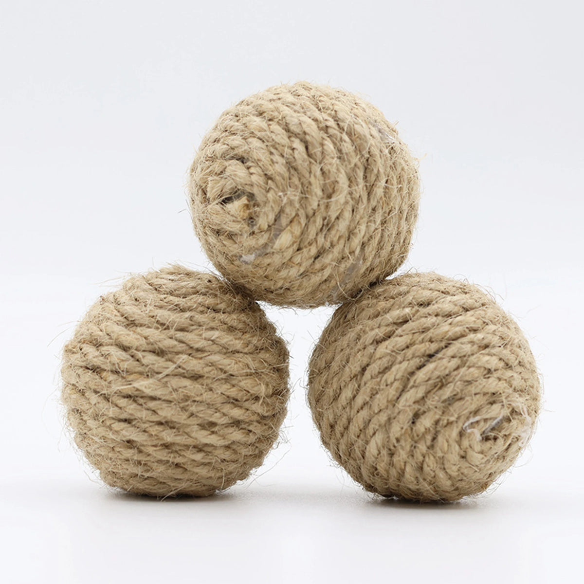 A stack of natural beige handwoven hemp and sisal cat toy balls.