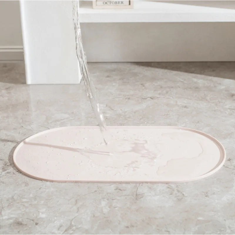 A pink non-slip waterproof feeding mat is being filled with water on a marble surface.