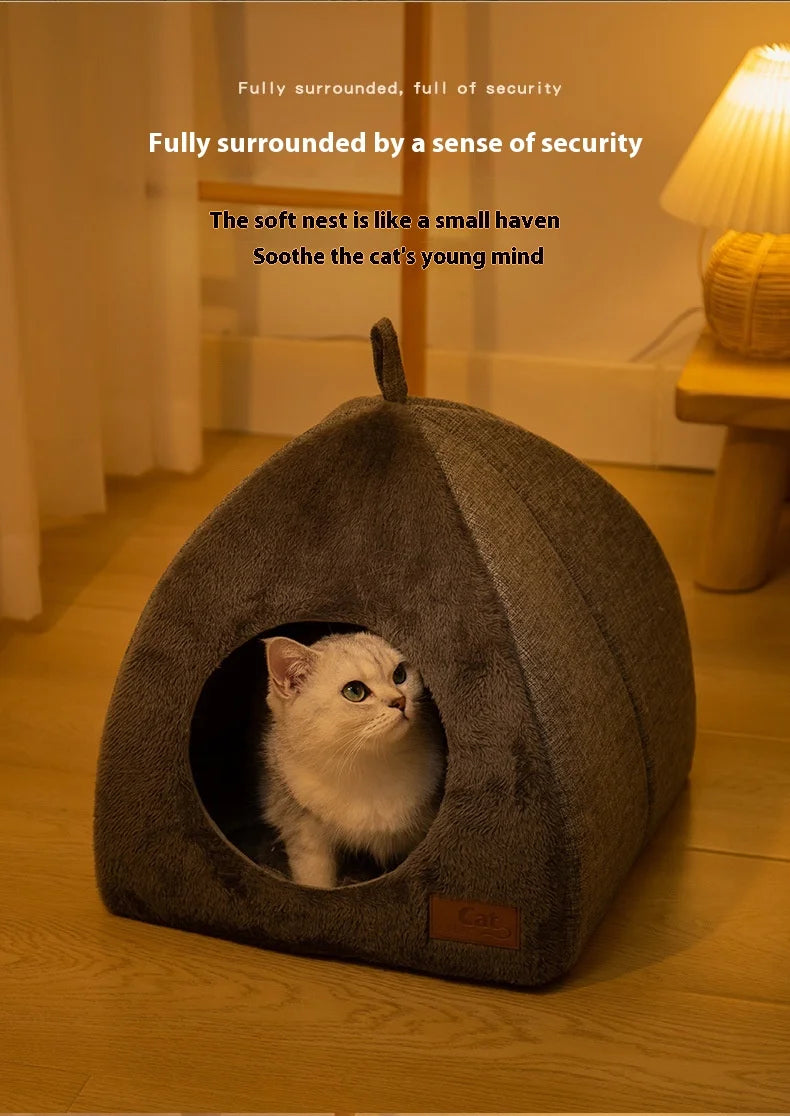 Un nid de chat en velours gris avec une entrée circulaire, contenant un chaton blanc.