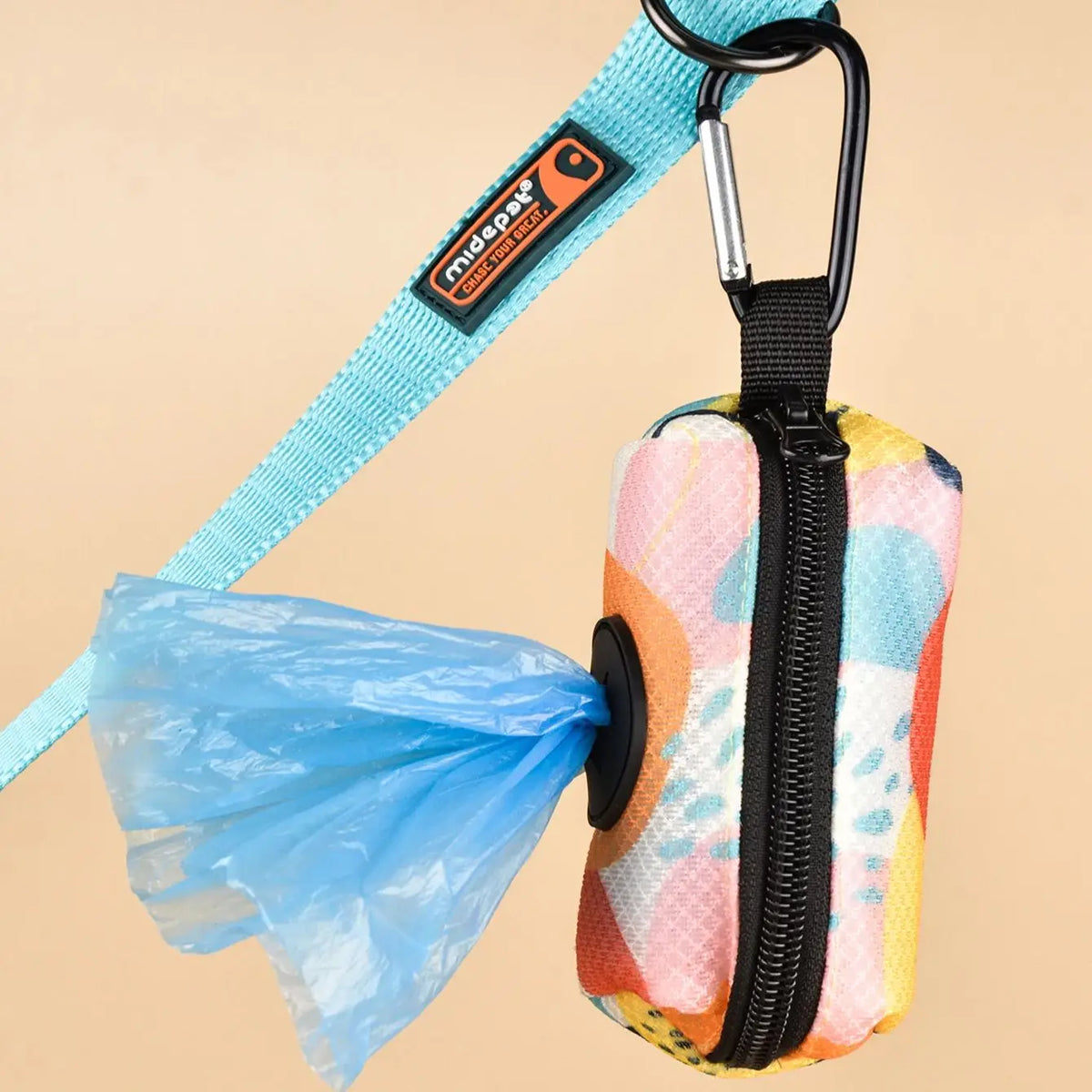 A blue leash clip attached to a fabric poop bag dispenser with a black zipper.