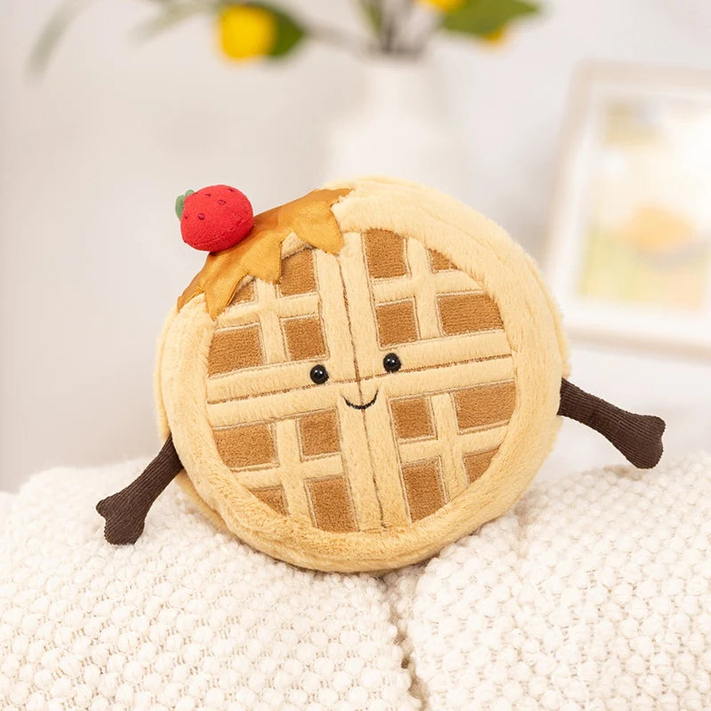A round, light tan plush toy shaped like a waffle with a smiling face and a small red strawberry on top.