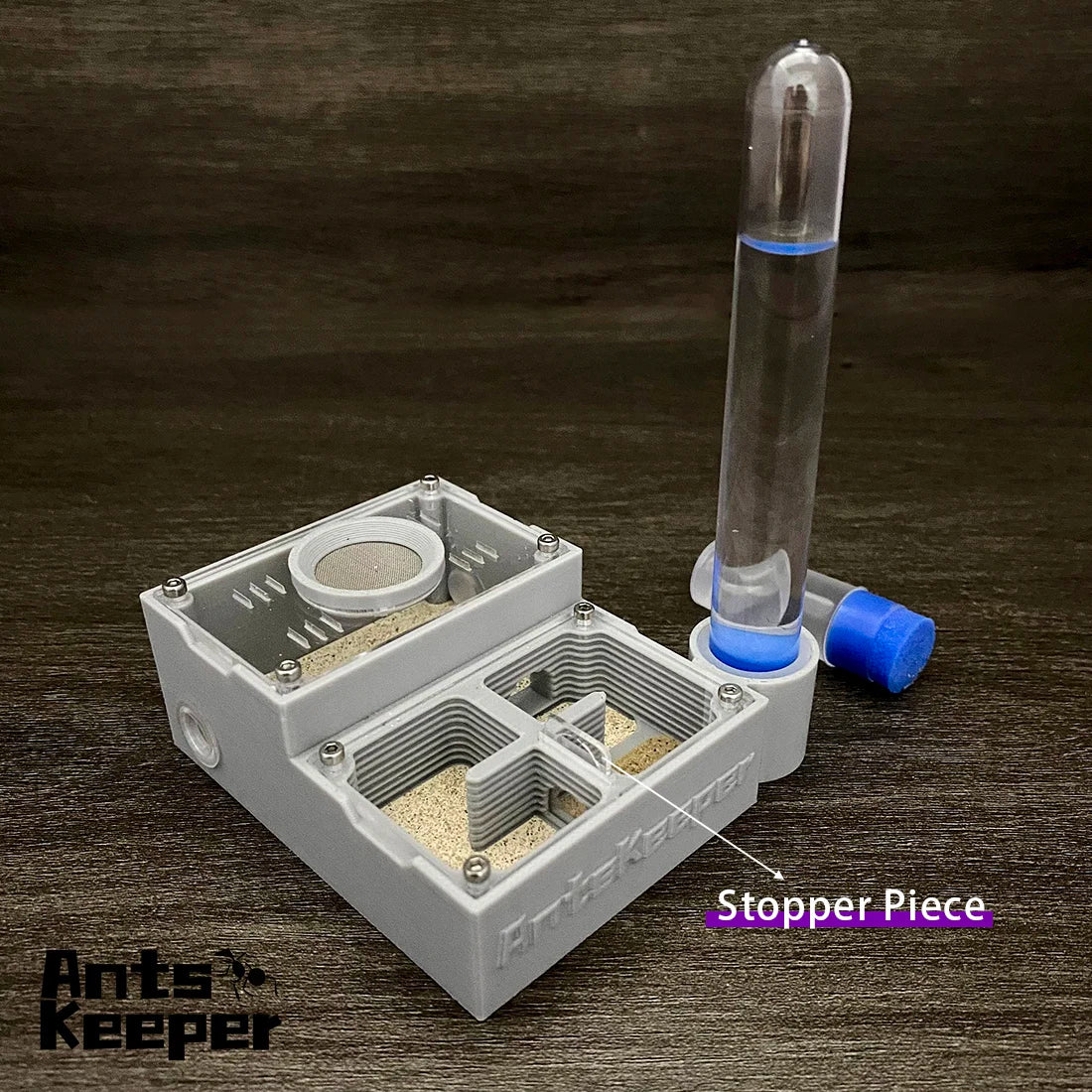 A clear glass tube with a blue liquid is placed inside a white plastic four-chamber observation farm device.