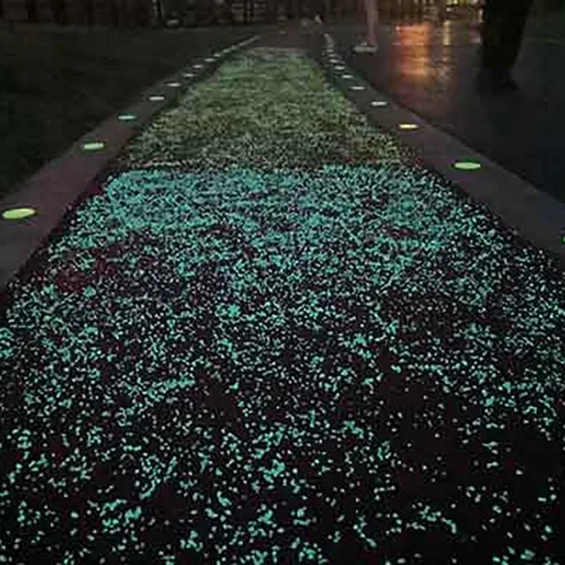 A pathway lined with glow-in-the-dark decorative pebbles illuminating a dark surface.