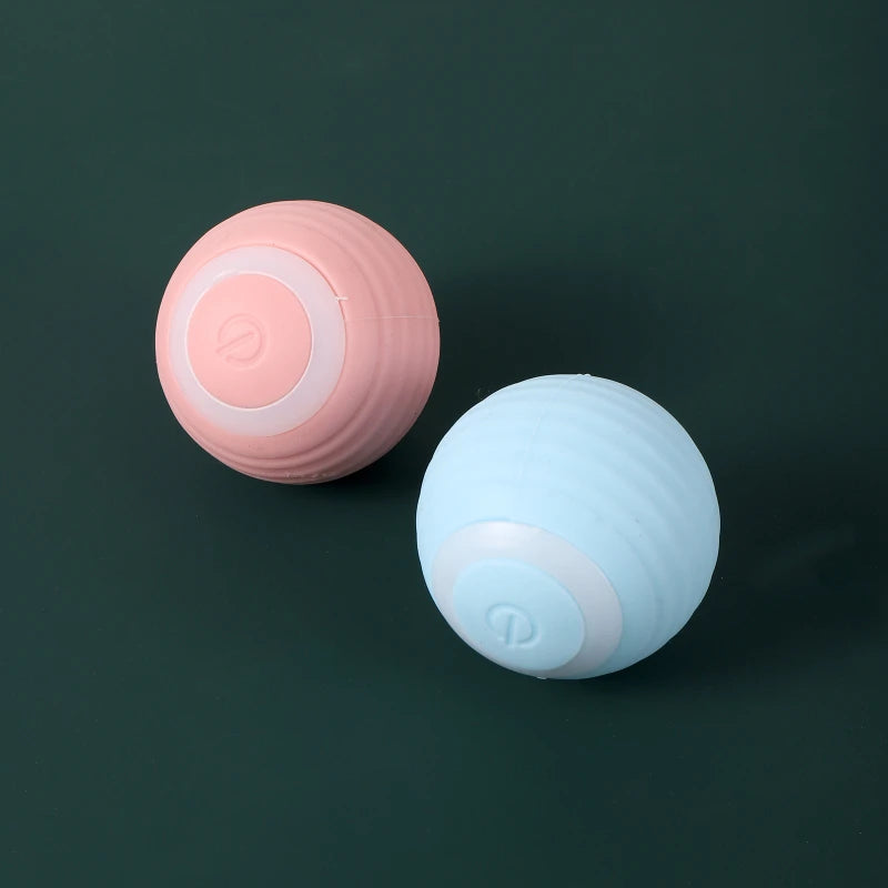 Zwei kugelförmige Katzenspielzeuge, eines rosa und eines hellblau, vor dunklem Hintergrund.