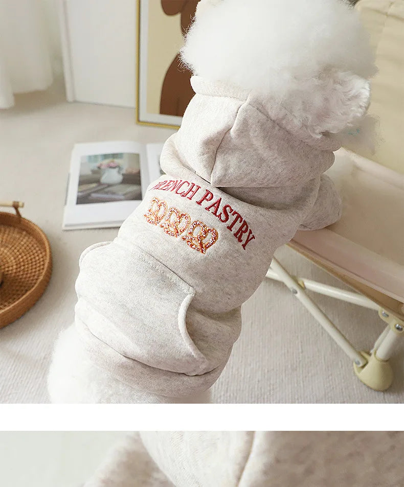 A light gray embroidered hoodie with a white faux fur hood and red lettering on the sleeve.