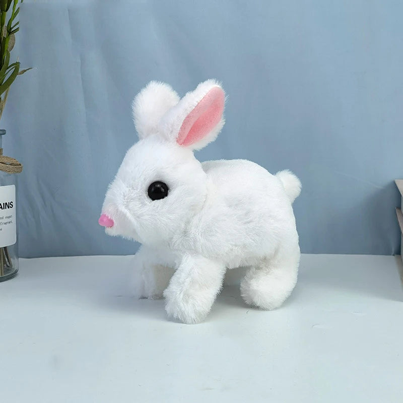 A white plush bunny toy with pink inner ears and black eyes sitting on a white surface.