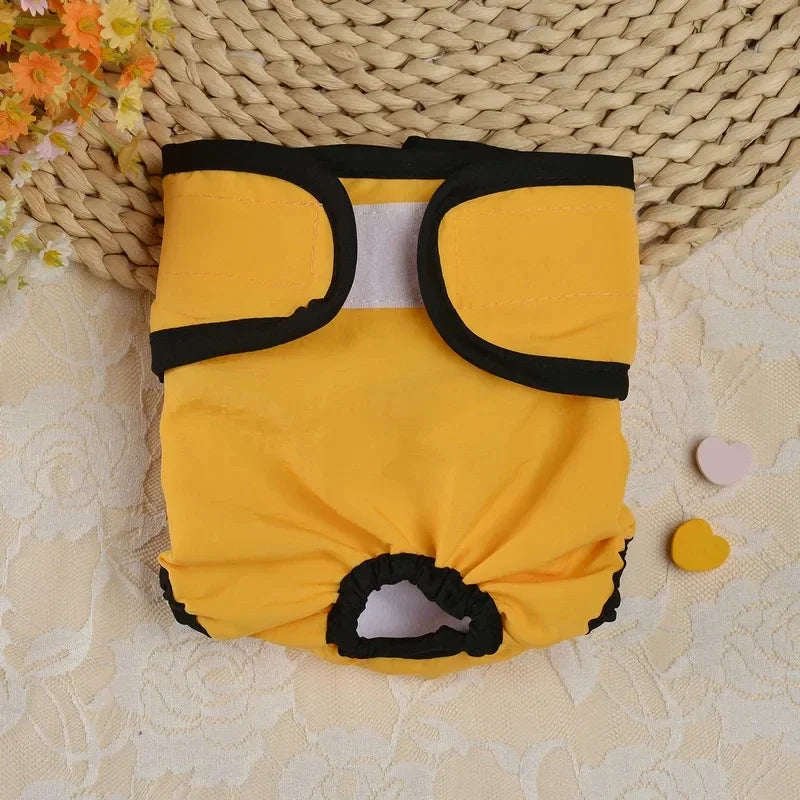 Couche assise pour chien jaune réutilisable avec bordure noire et insert blanc, posée sur un tapis tissé.