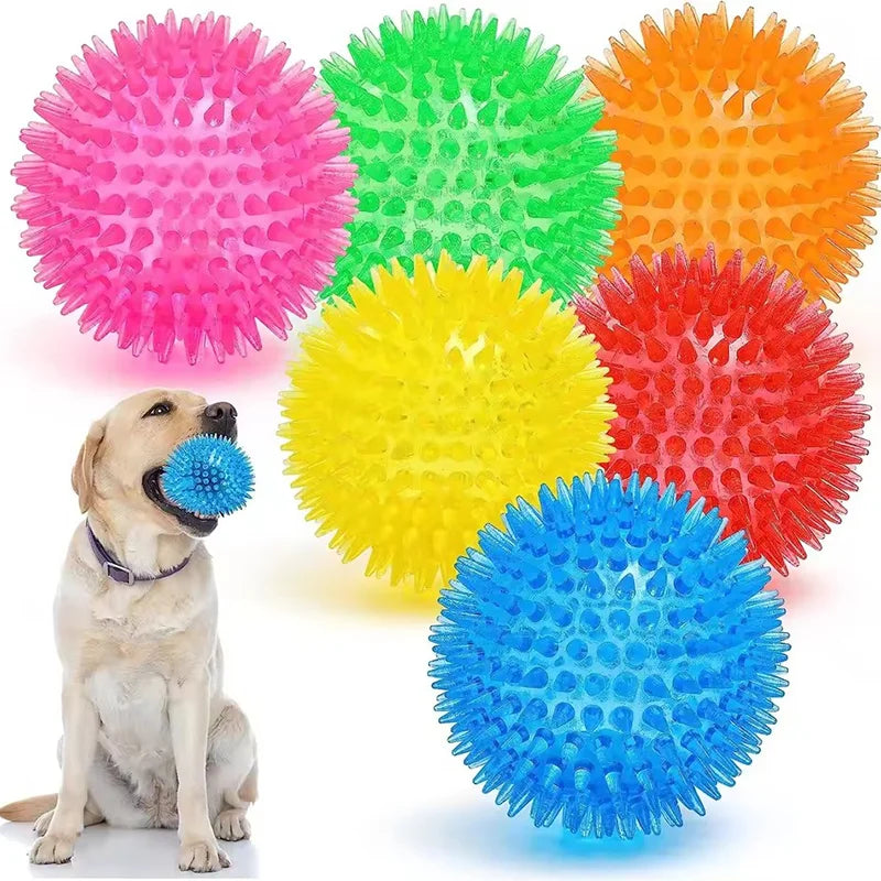 A collection of brightly colored spiky squeaky dog toys including pink, green, orange, and yellow balls.