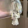 A clear glass keychain featuring a white dog design suspended from strands of pearl beads and a heart charm.