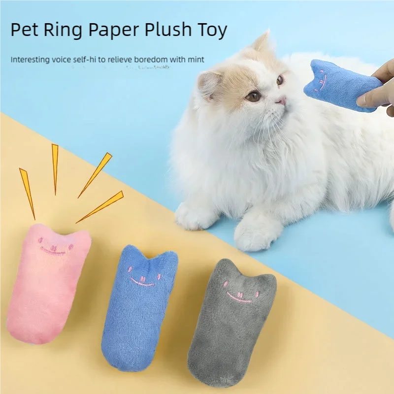 Ein flauschiger weißer Kater liegt neben mehreren farbenfrohen Papier-Plüschspielzeugen für Haustiere.