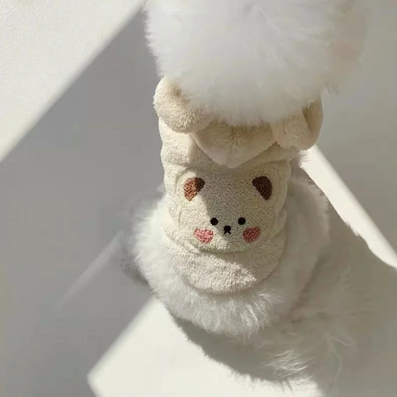 Gros plan d'un pull en polaire polaire pour chien, avec une bordure de fourrure blanche et des détails brodés marron.