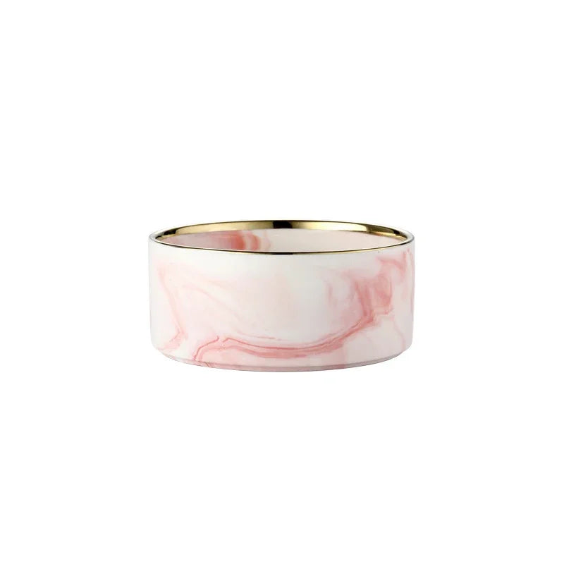 A set of double pet bowls made of marbled pink ceramic with a gold rim and a wooden stand.
