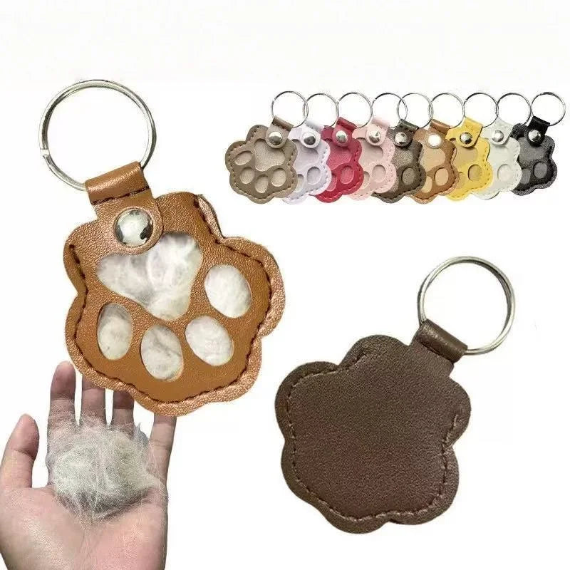 A collection of leather paw print airtag keychains and a single brown leather paw print keychain held in a hand.