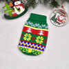 A knitted green and red winter dog sweater with colorful Nordic patterns, placed next to Christmas ornaments.