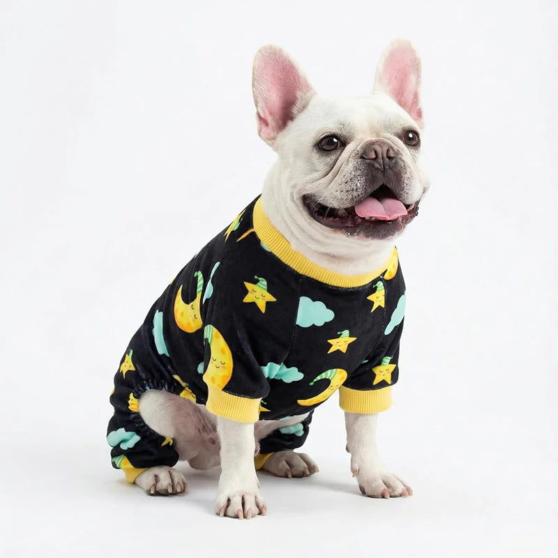 A French Bulldog wearing black stretchy dog pajamas with a moon and star print and yellow trim.