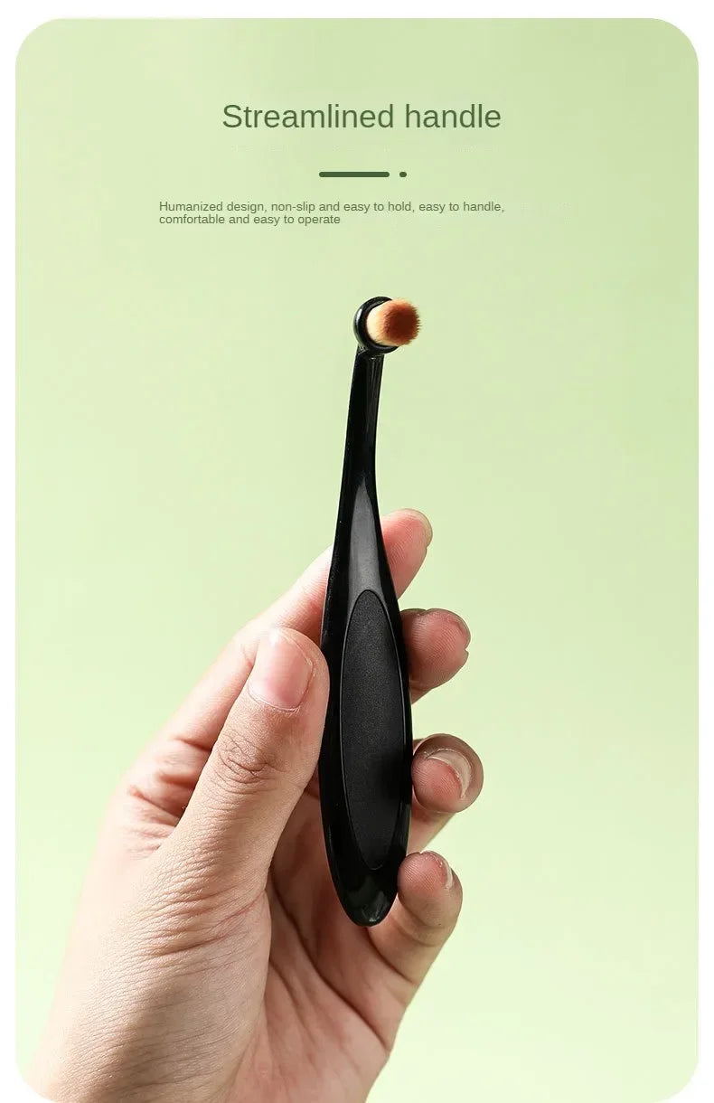 A hand holds a black pet tear stain remover brush with a soft, light brown tip.