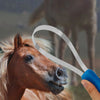 A hand holds an expandable dual-sided grooming comb with silver bristles, positioned near a horse's head.