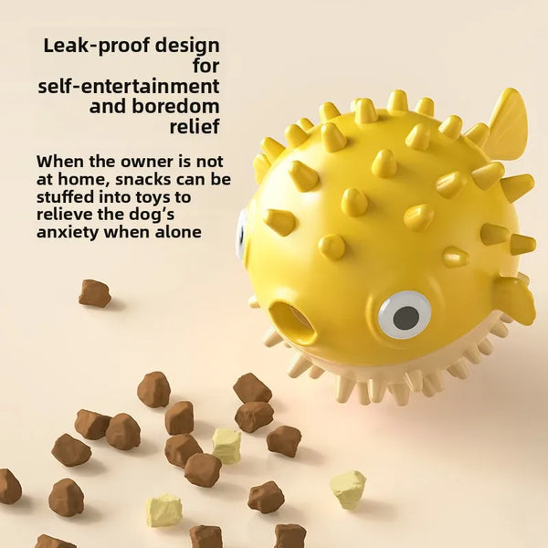 A yellow, spiky fish-shaped treat dispenser is shown with scattered dog treats on a light surface.