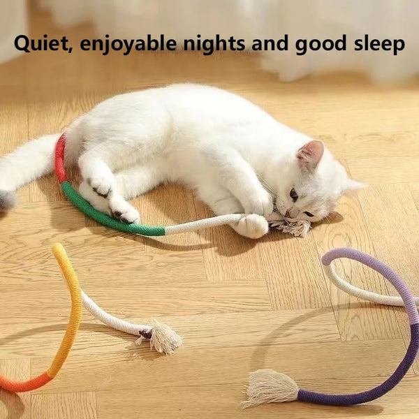 A white cat is lying on a wooden floor near several organic cotton cat chew ropes with refillable catnip pouches.