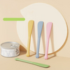 A set of five multi-purpose pet feeding spoons in various pastel colors, including a green one, displayed against a light bac