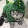 A tabby cat wearing a green cartoon animal costume jumpsuit with large eyes and pointed ears.