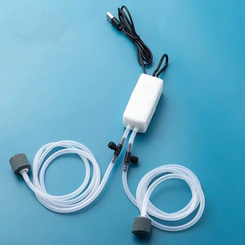 A white USB aquarium air pump with tubing and air stones is shown against a blue background.
