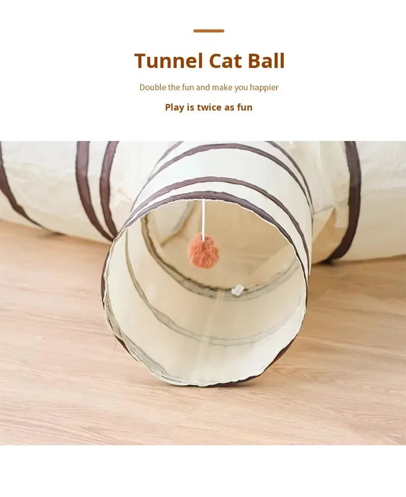 A beige fabric tunnel for cats is shown, with a fluffy pom-pom at the entrance.