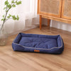 A navy blue faux fleece pet sofa bed with a waterproof base resting on a light wood floor.