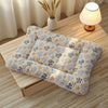 A beige and blue patterned plush double-sided pet blanket resting on a wooden surface next to a lamp.