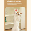 A white cat is playing with a red ball toy in a bright indoor setting.