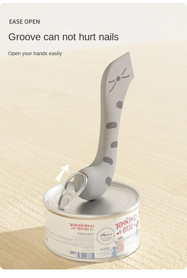 A silver multifunctional pet feeding spoon with a can opener and sealing lid is shown on a wooden surface.