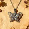 Silver butterfly ashes pendant necklace hanging from a chain on parchment paper