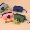 A collection of colorful fabric pouches and a green carabiner dog poop bag dispenser on a beige background.