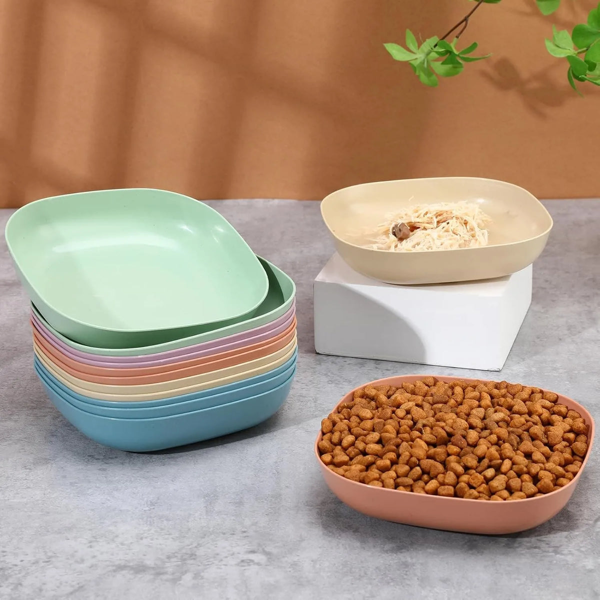 A set of non-slip shallow bowls for pets, including multiple colored bowls and a bowl filled with dry food.