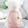 Collar de perro de peluche blanco esponjoso con tela de punto rosa y ribete rojo sobre una almohada blanca.