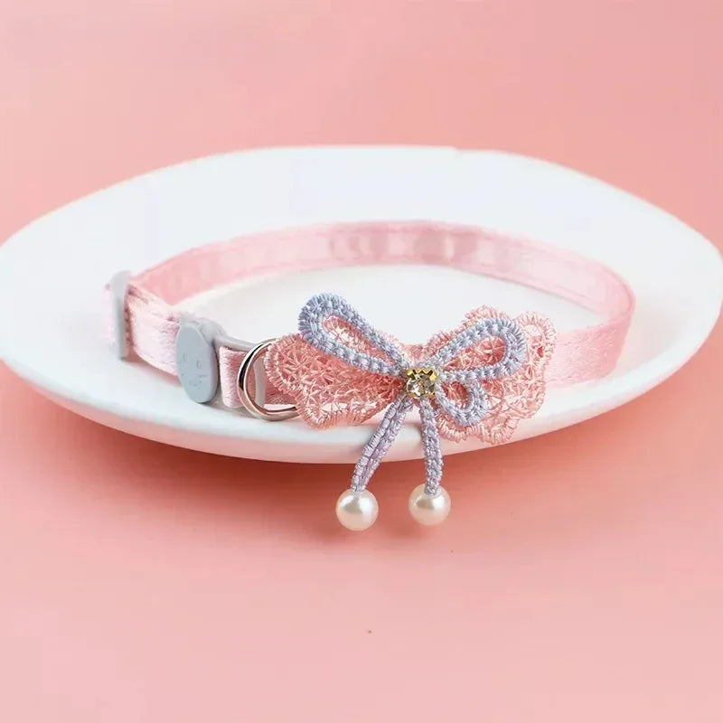 Pink lace bow cat collar featuring a bead charm and dangling bell.