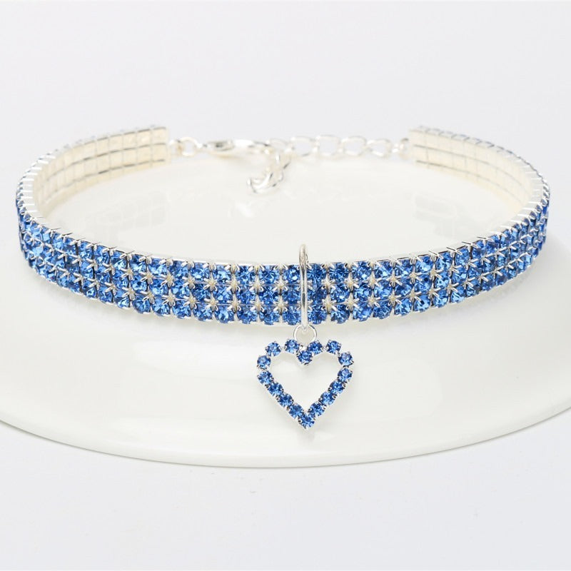 A sparkling blue rhinestone collar for dogs or cats, displayed on a white plate.