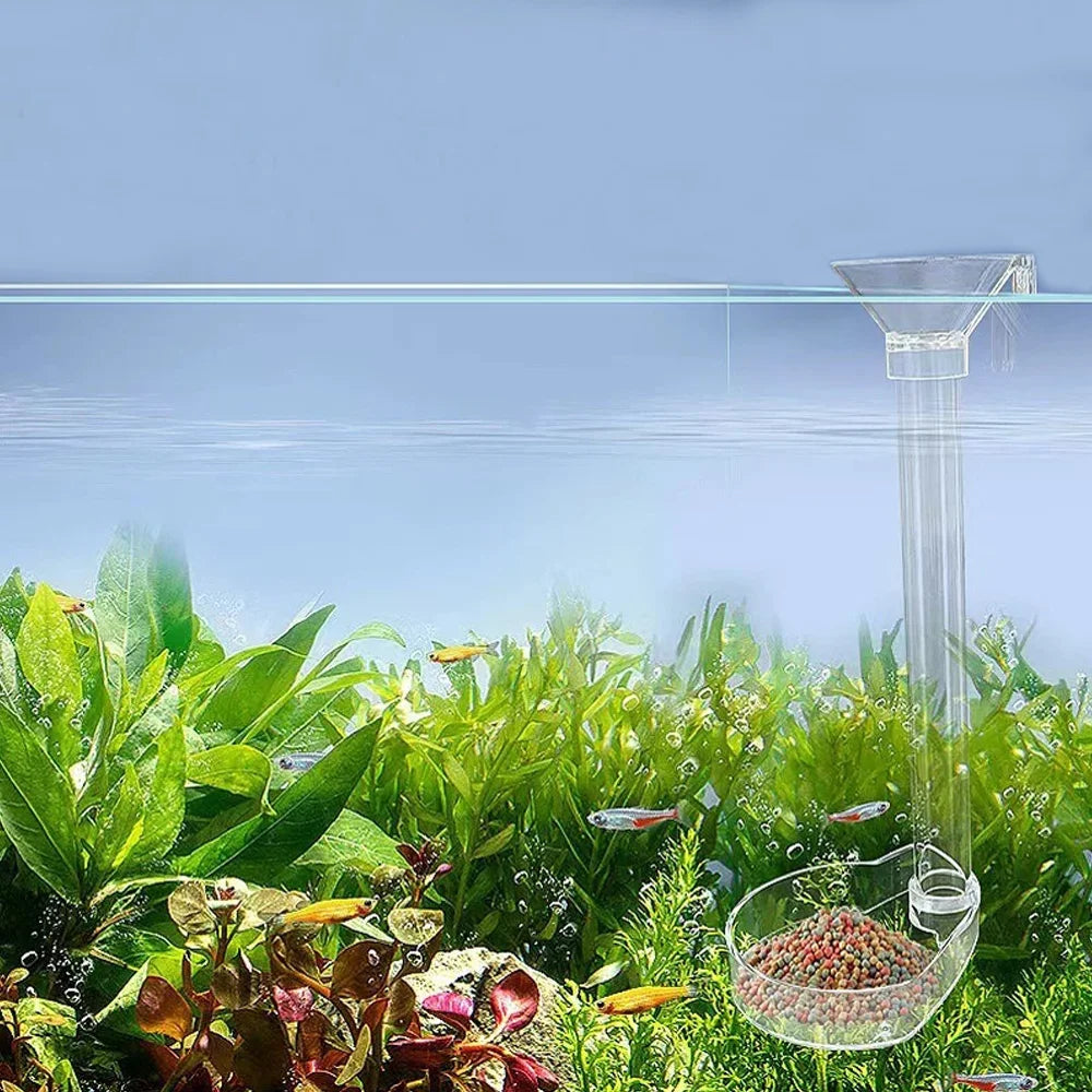 An adjustable aquarium feeder with a transparent tube is shown above lush green aquatic plants.