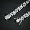 Rapproché d'un collier Cuban link argenté avec diamants pavés sur fond noir.