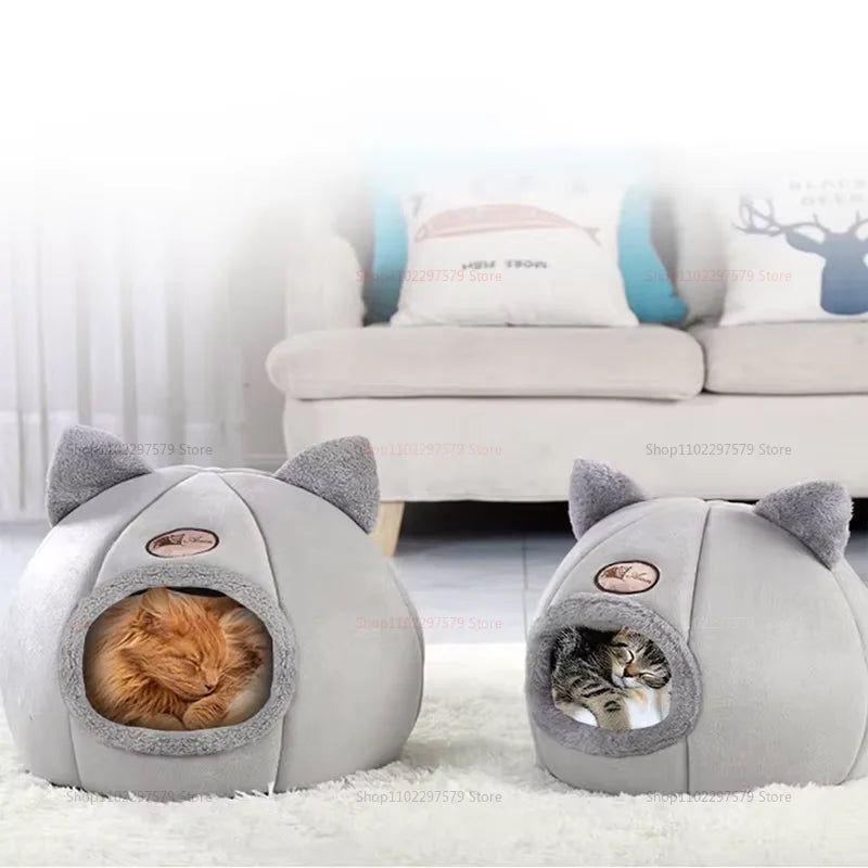Un lit-nid de chat en peluche gris avec des formes d'oreilles, doté d'une entrée ouverte pour un petit chaton.