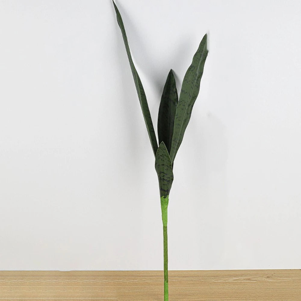 An artificial snake plant with long, dark green leaves and a slender stem against a white background.