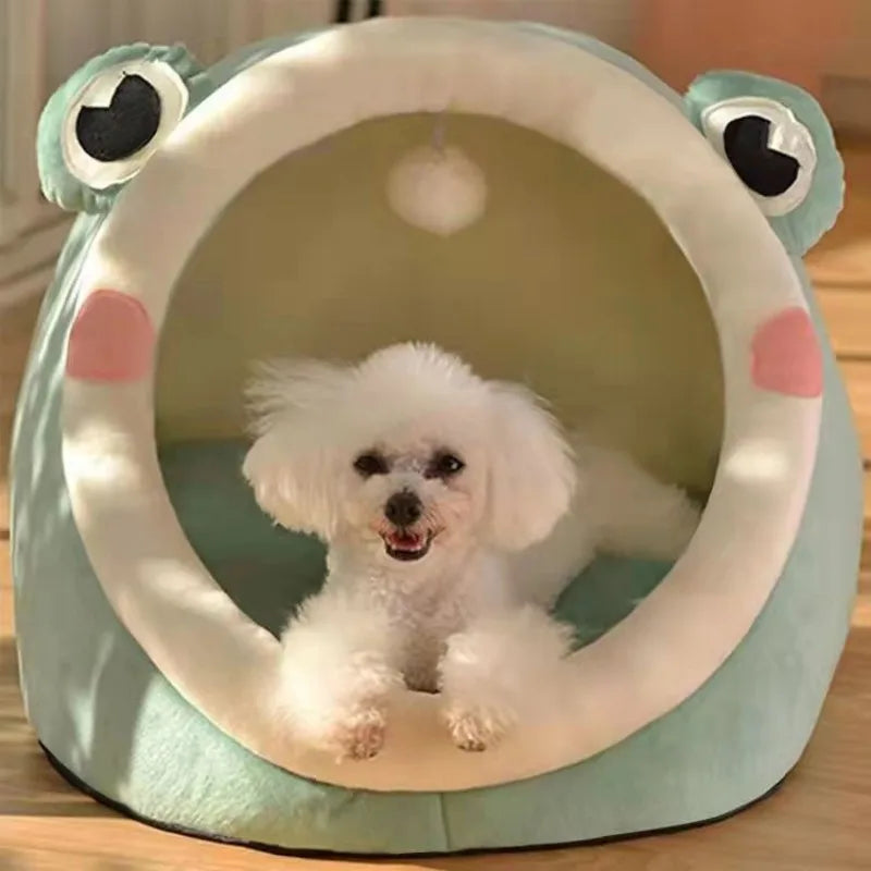 A fluffy white dog is resting inside a light blue pet cave bed shaped like a frog.