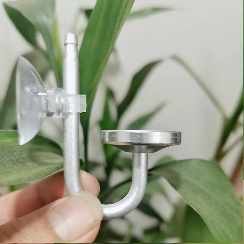 Silberner Aluminium-CO2-Diffusor für Aquarium, gehalten von einer Hand vor grünem Pflanzenhintergrund