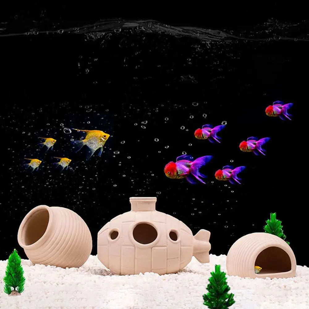 A ceramic aquarium shrimp hideaway cave is shown resting on white sand with green foliage.