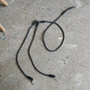 A black hands-free dog leash with a reflective stripe is laid out on a gray concrete surface.