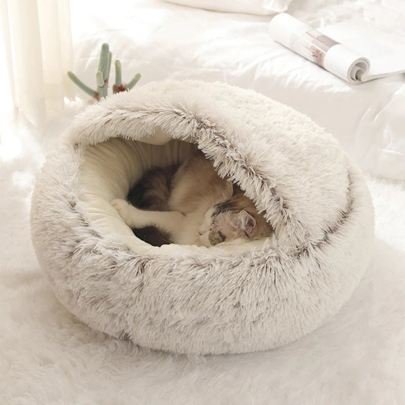 A round, fluffy white plush pet bed with a removable cover is shown resting on a white surface.
